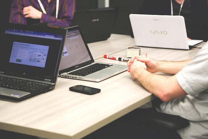 People sitting at a table with laptops during a meeting.