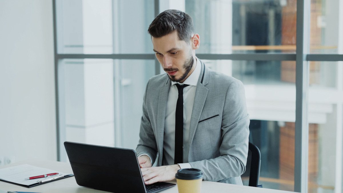 Businessman working on a laptop in a modern office setting.